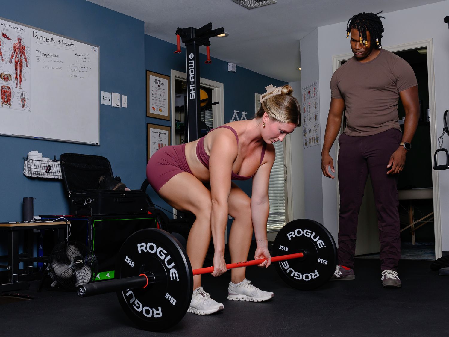A client lifting a loaded barbell while Brandon coaches from the side in the CrosaCore clinic