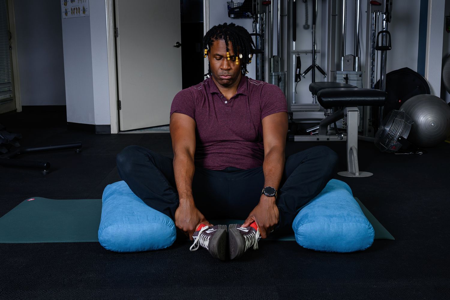 Brandon guiding a seated mobility position on a mat with supportive bolsters